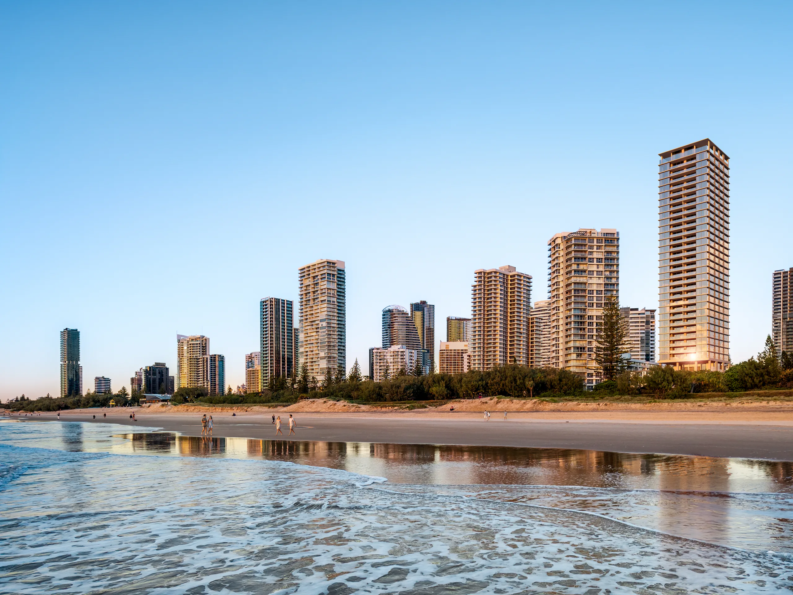 Golden hour surf rising to reveal the Breeze tower on the Broadbeach skyline