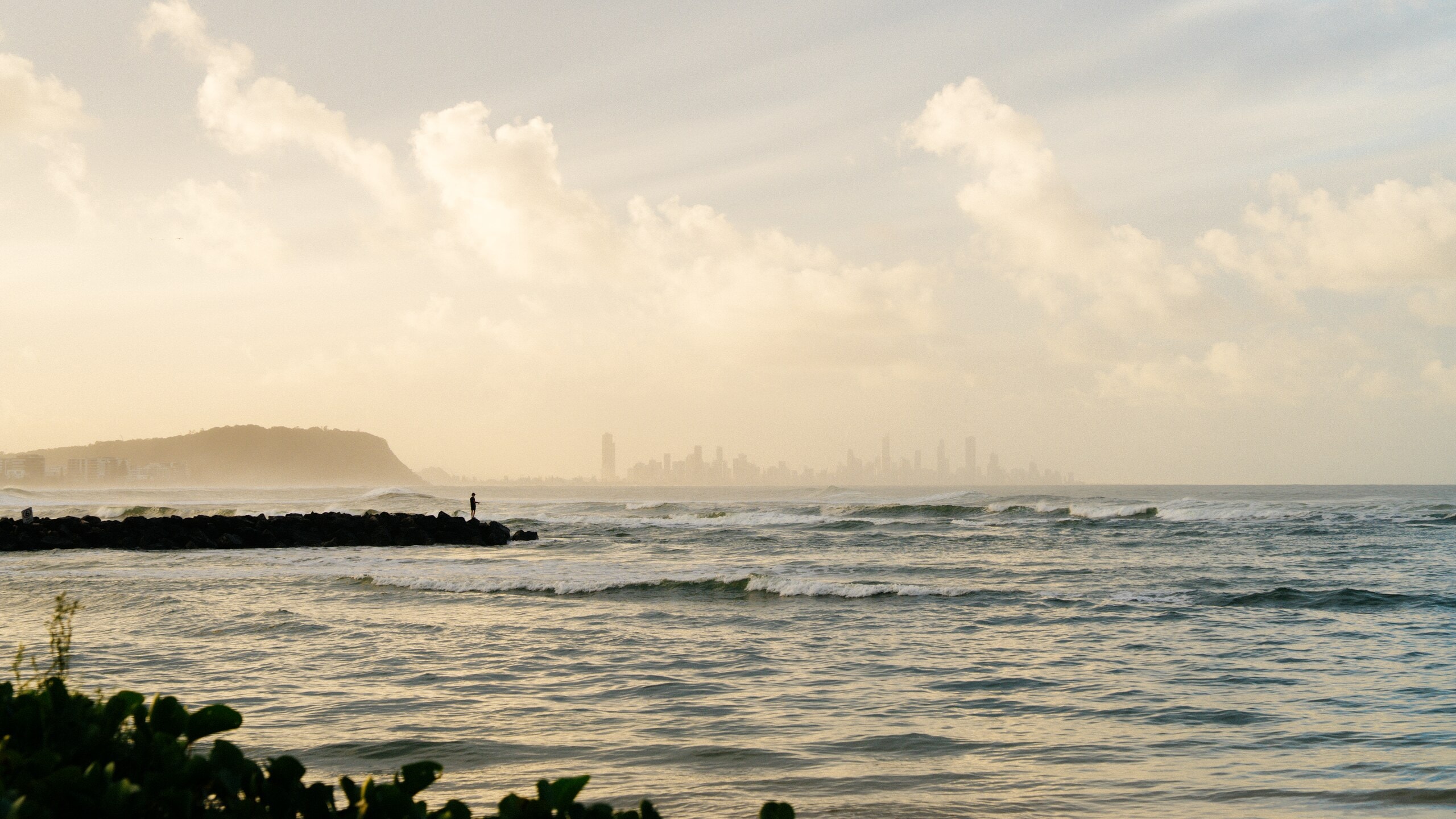 Burleigh headland and the Surfers Paradise skyline at dawn, seen across the surf